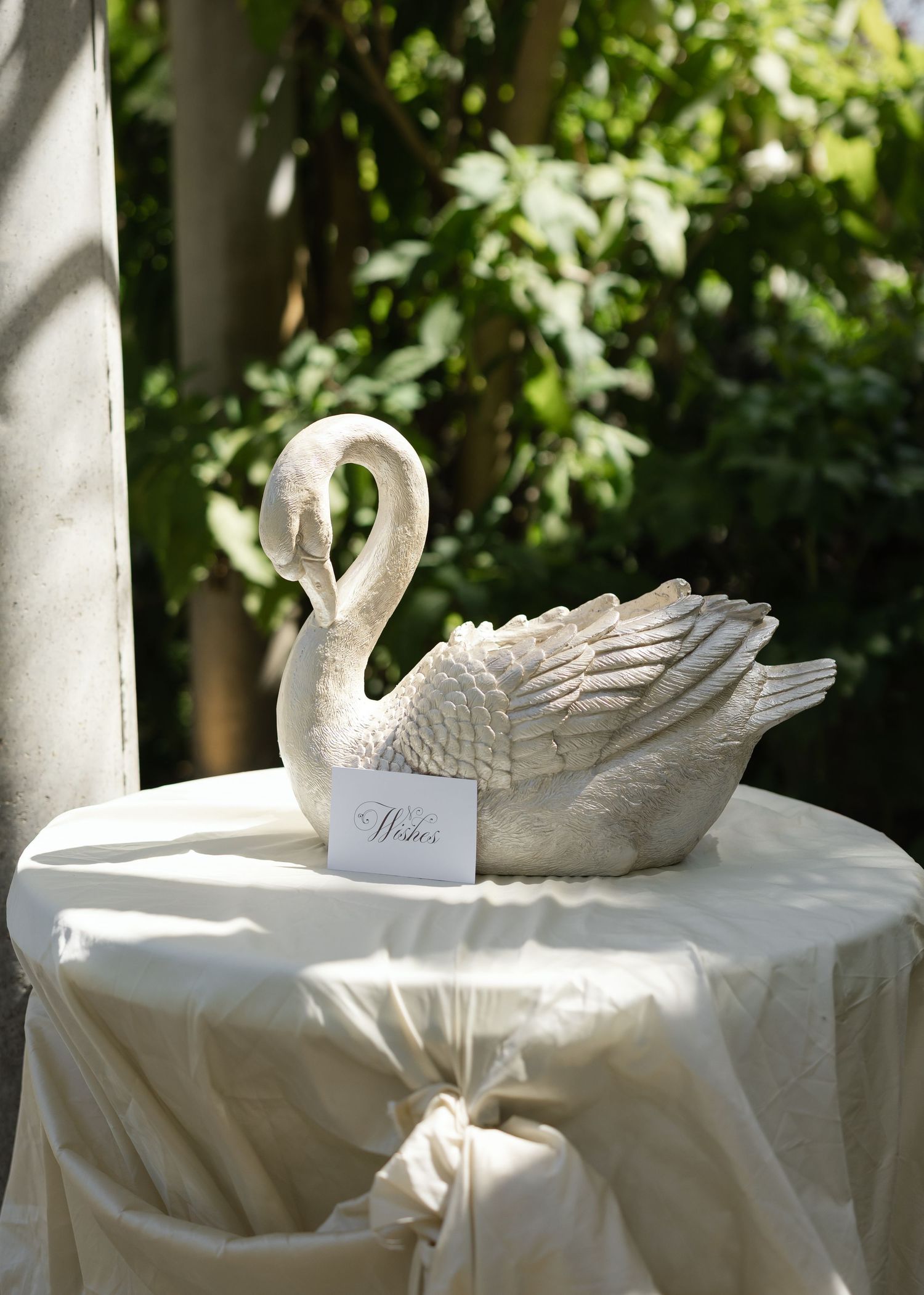 White decorative swan ornament sitting on a draped tablecloth with lush greenery in the background at Al Ru Farm in Adelaide.