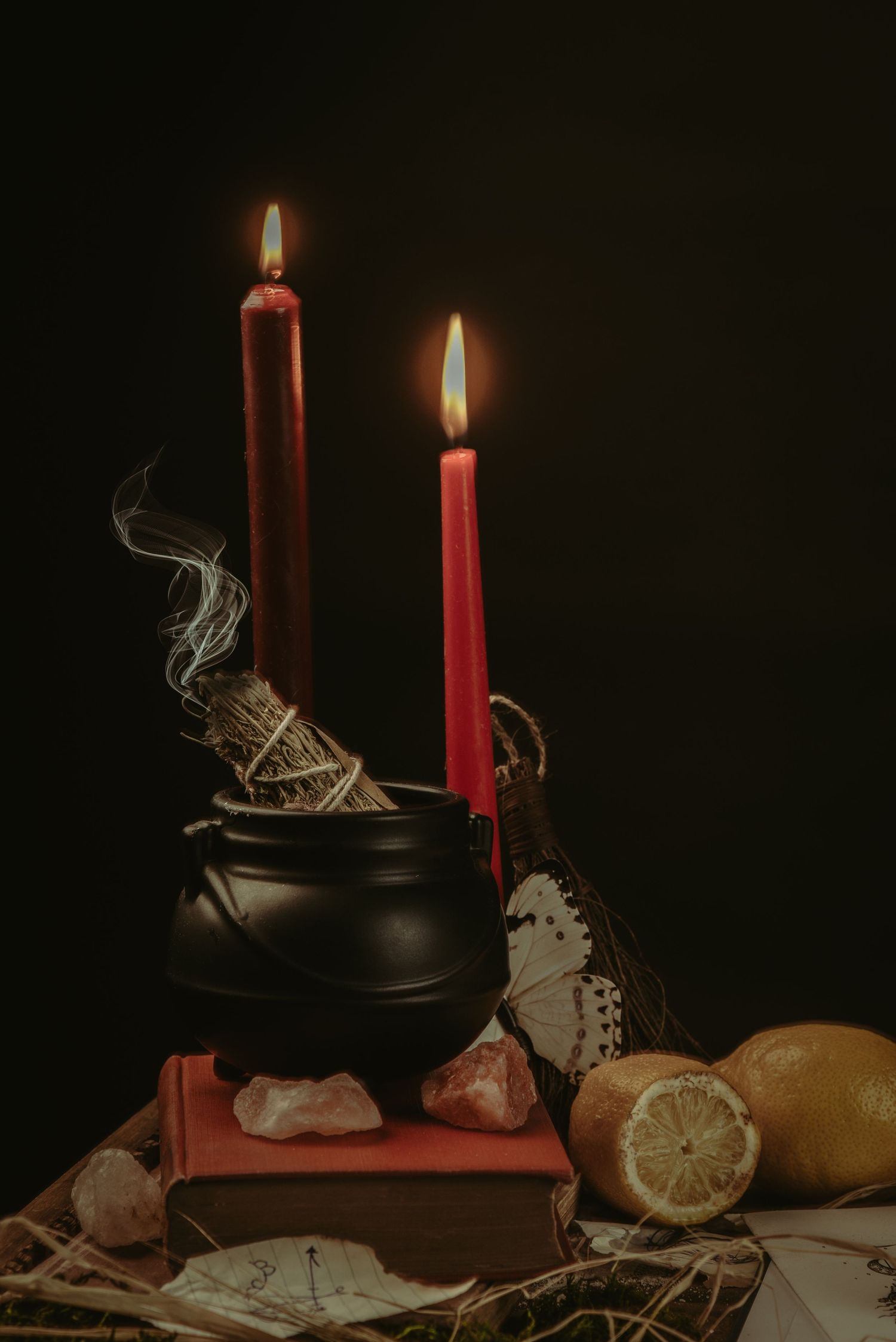 Still life with red candles, citrus fruits and vintage objects against dark background.
