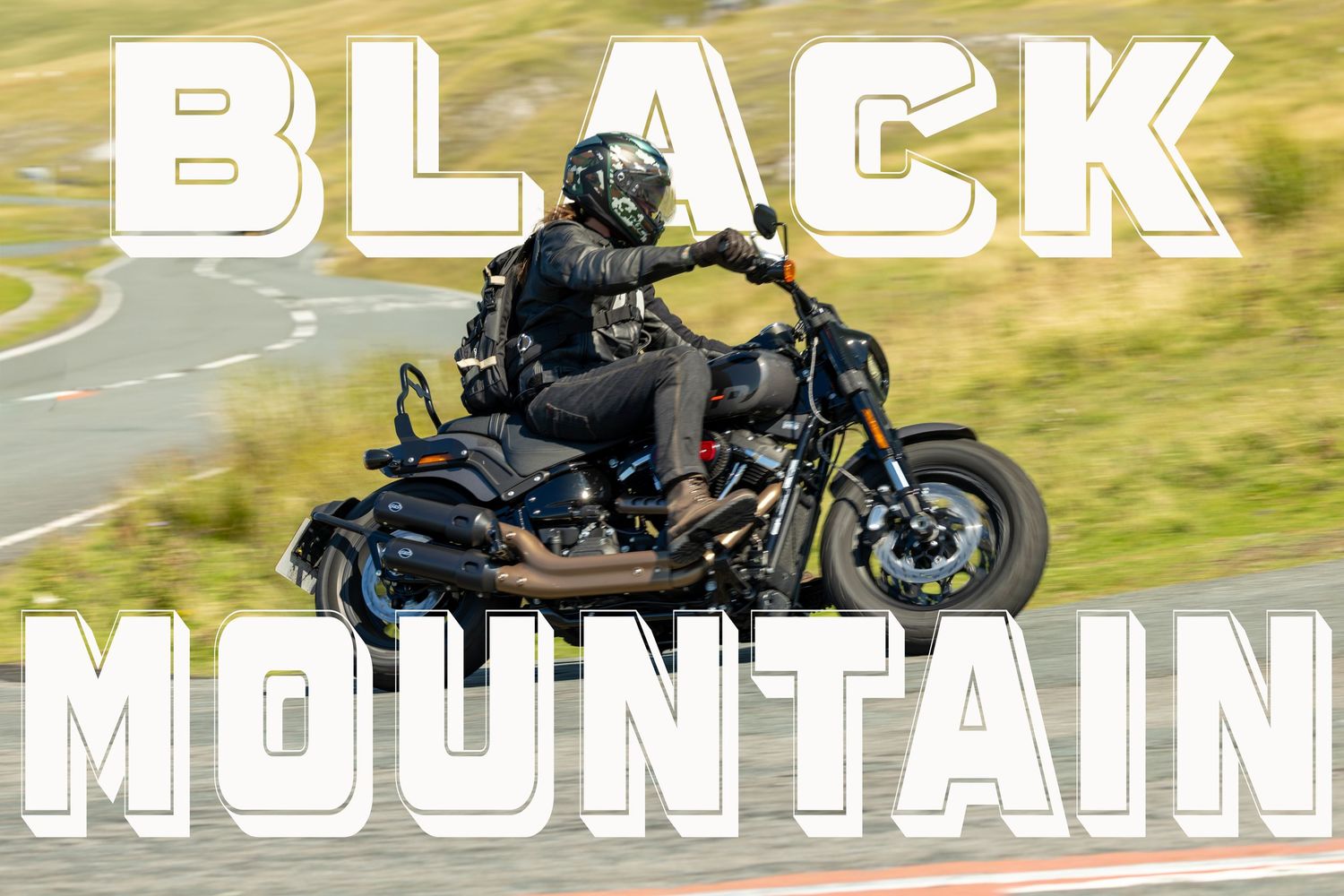 A motorcyclist rides a Monyash B5055 bike on a rural country road with another rider visible in the distance.