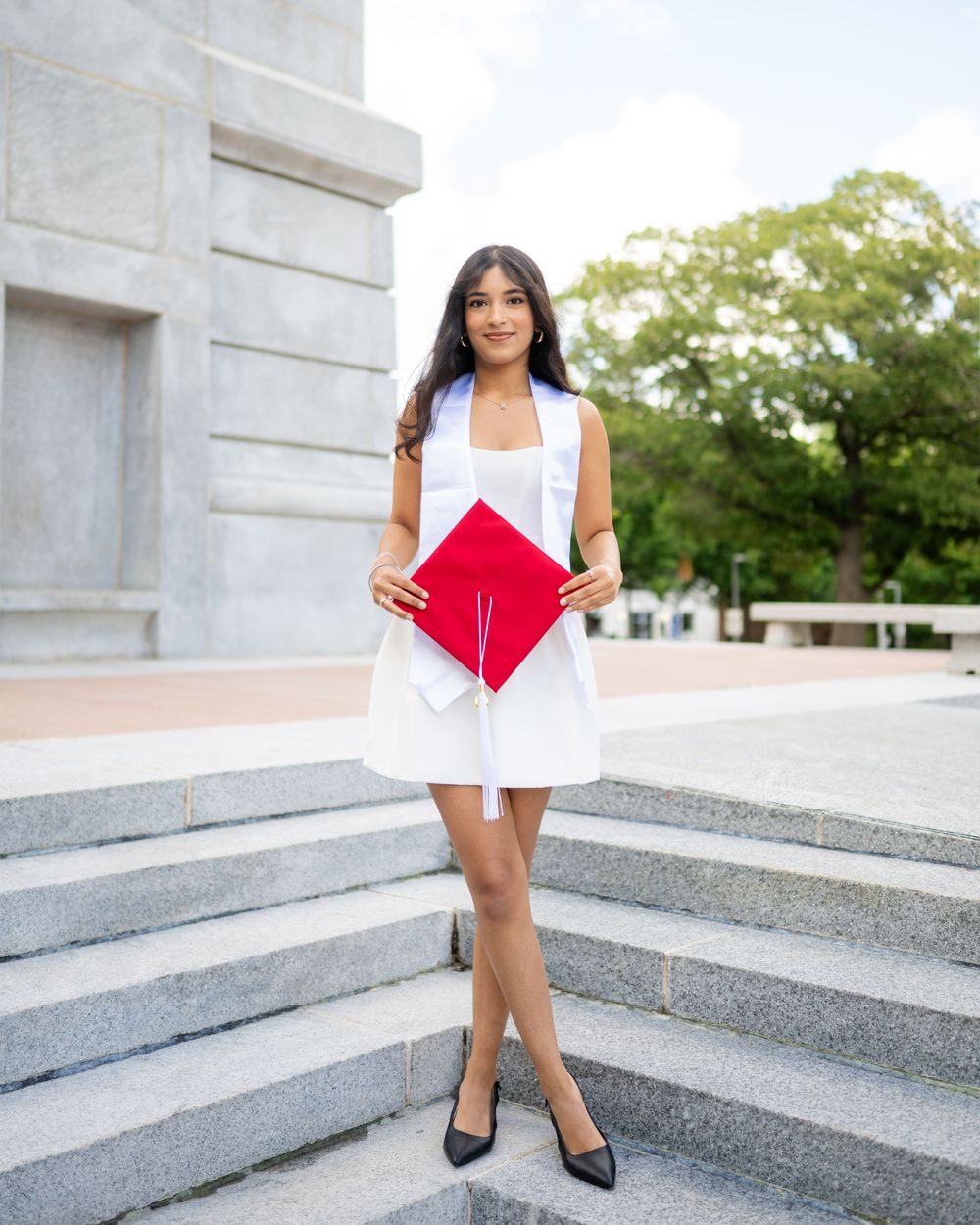 A graduation photo series showing someone in a white dress and red graduation cap posing on concrete steps outdoors.