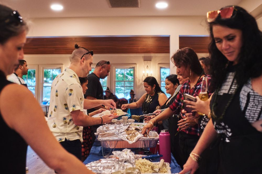 Wedding guests serve themselves at a buffet table indoors.