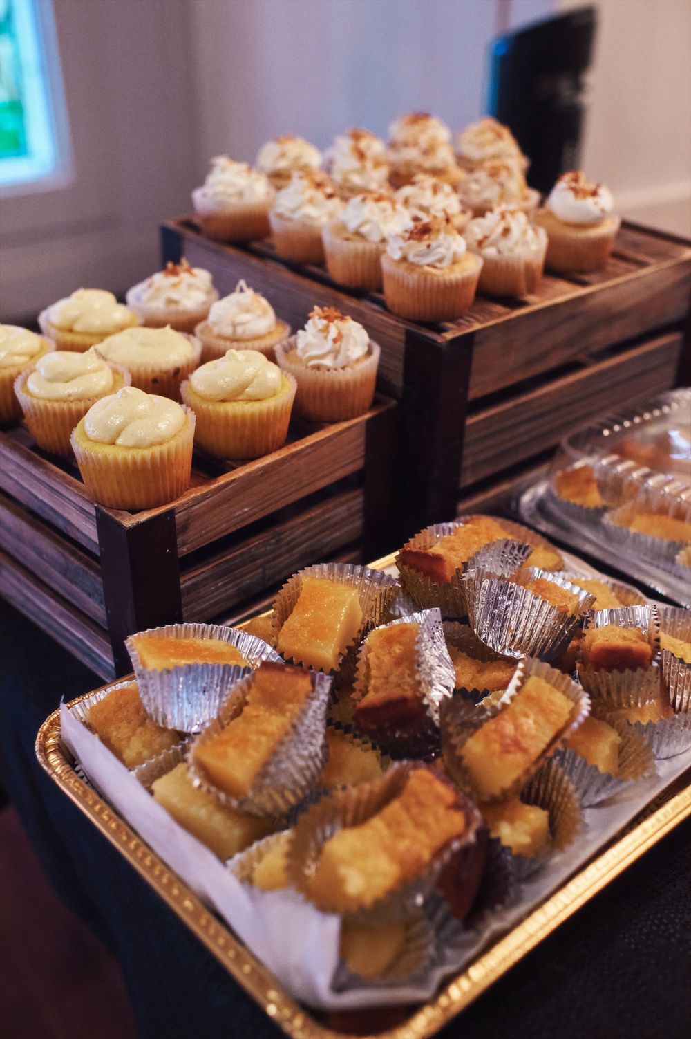 Wedding dessert display featuring cupcakes and pastries arranged on wooden stands.