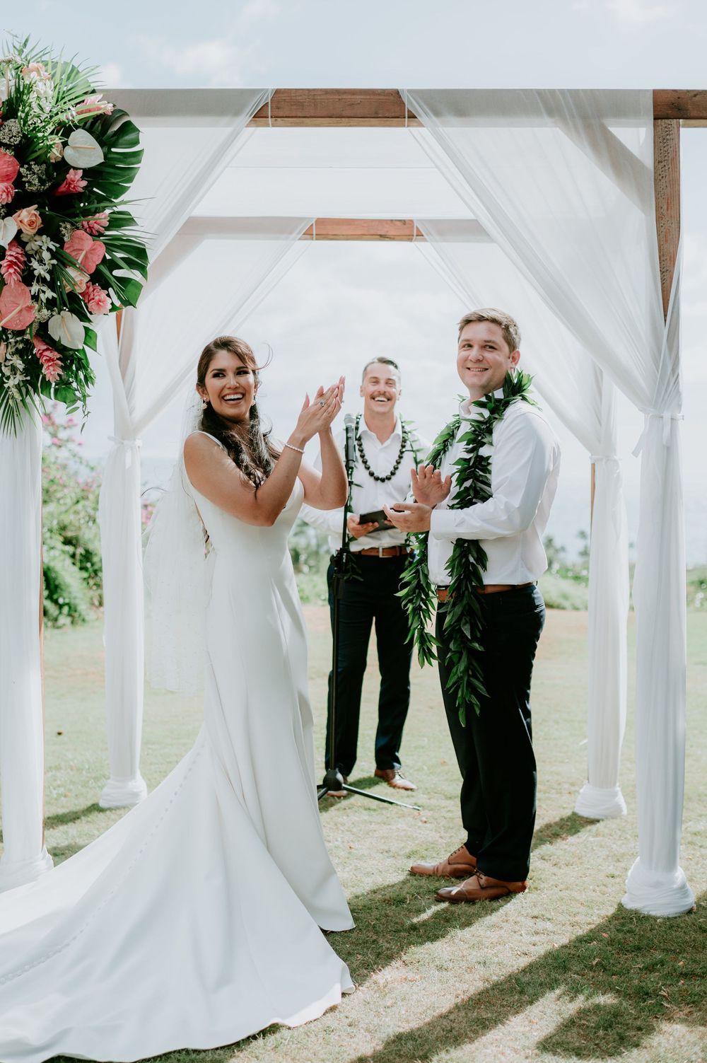White wedding arbor decorated with pink flowers frames outdoor ceremony moments.