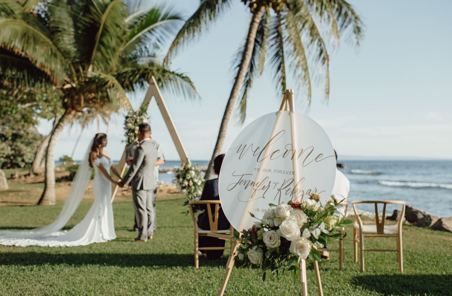 Beach wedding ceremony setup with palm trees and ocean backdrop.