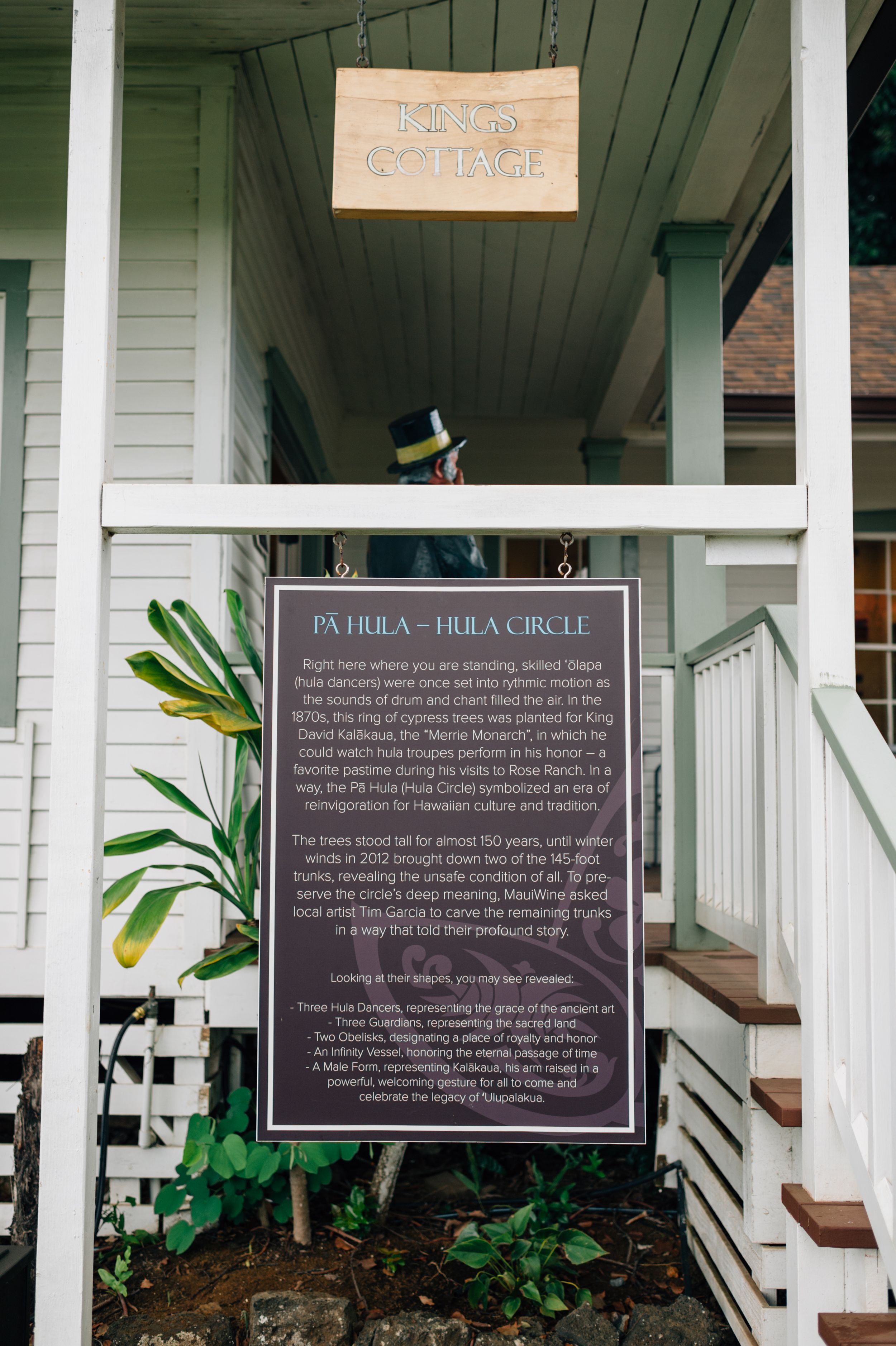 Historic informational plaques and signs displayed on white wooden porch railings.