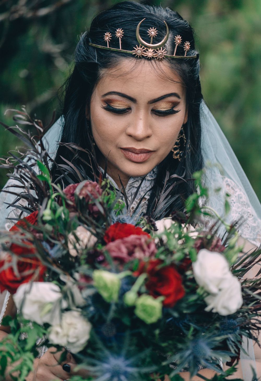 Elegant bridal details featuring a celestial crown and burgundy floral bouquet against natural greenery.