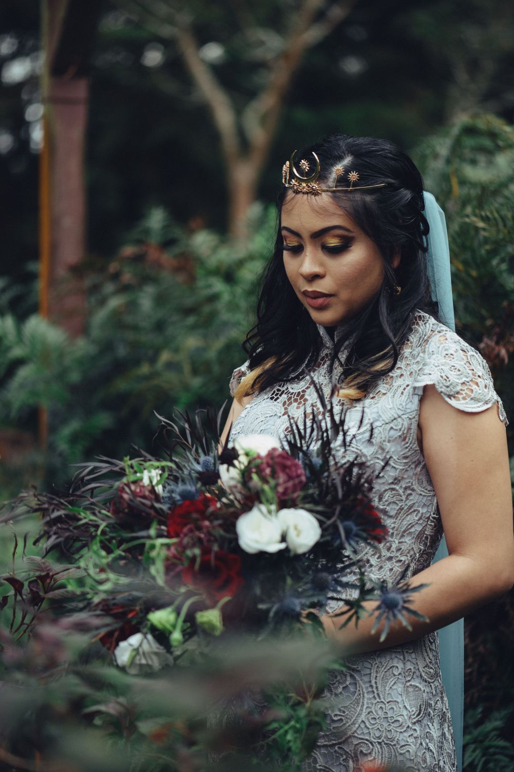 Artistic bridal photography featuring intricate lace dress and moody floral arrangements.