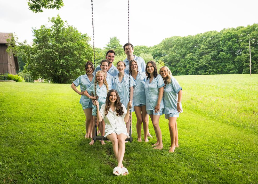Bridal party in matching robes posing outdoors on a lush green lawn before the wedding.