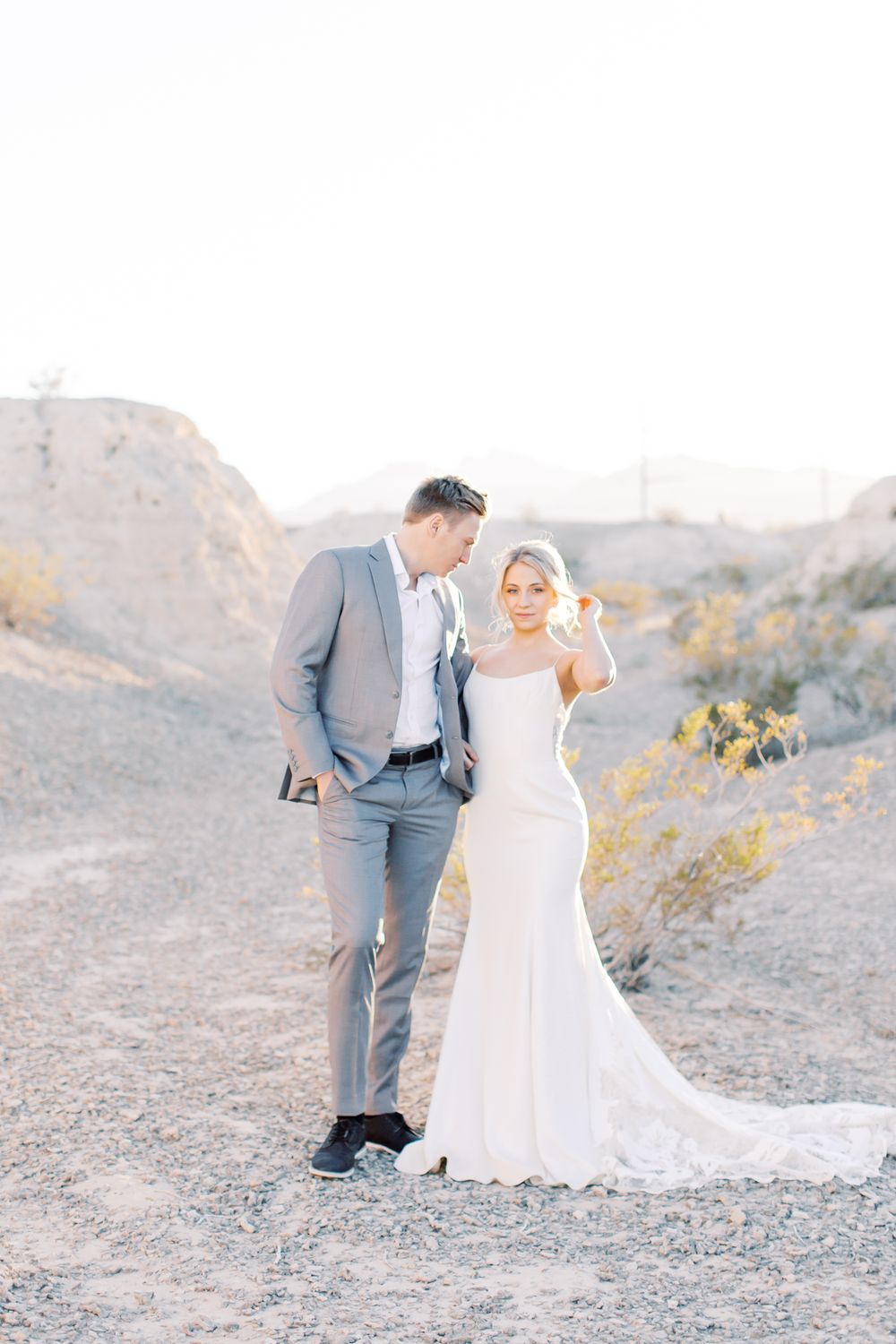 A couple poses together in a desert landscape during their wedding photoshoot.