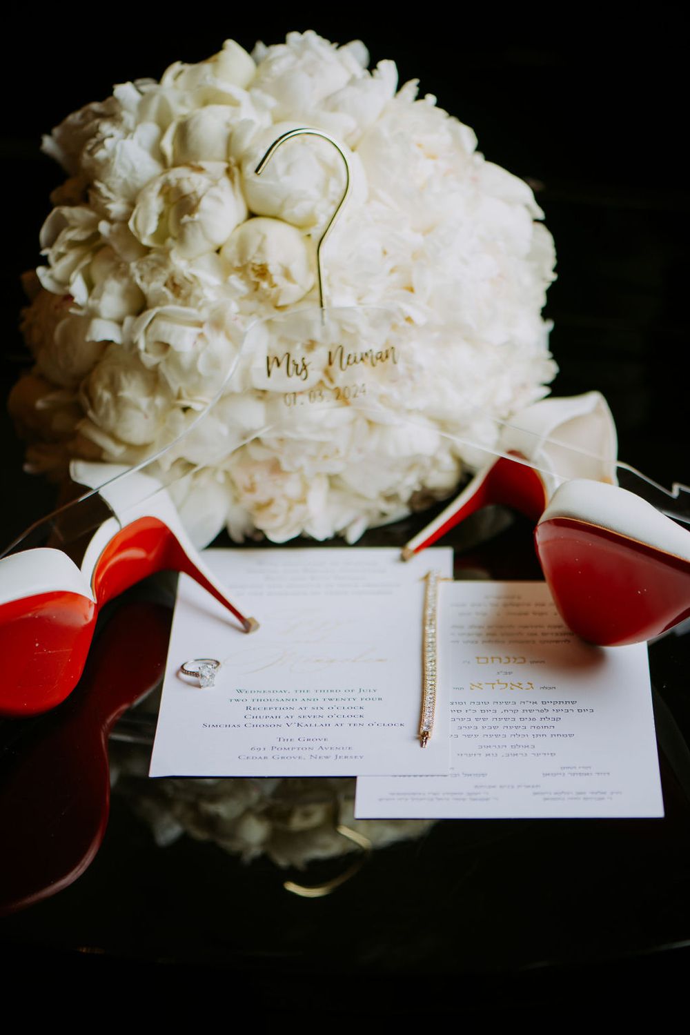 Wedding invitation cards displayed with white hydrangea flowers and red ribbon in dramatic lighting.