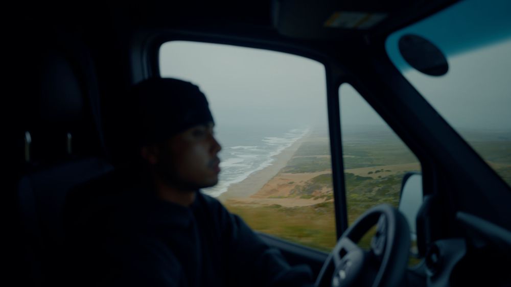Interior view of a vehicle dashboard while driving through a mountainous landscape.