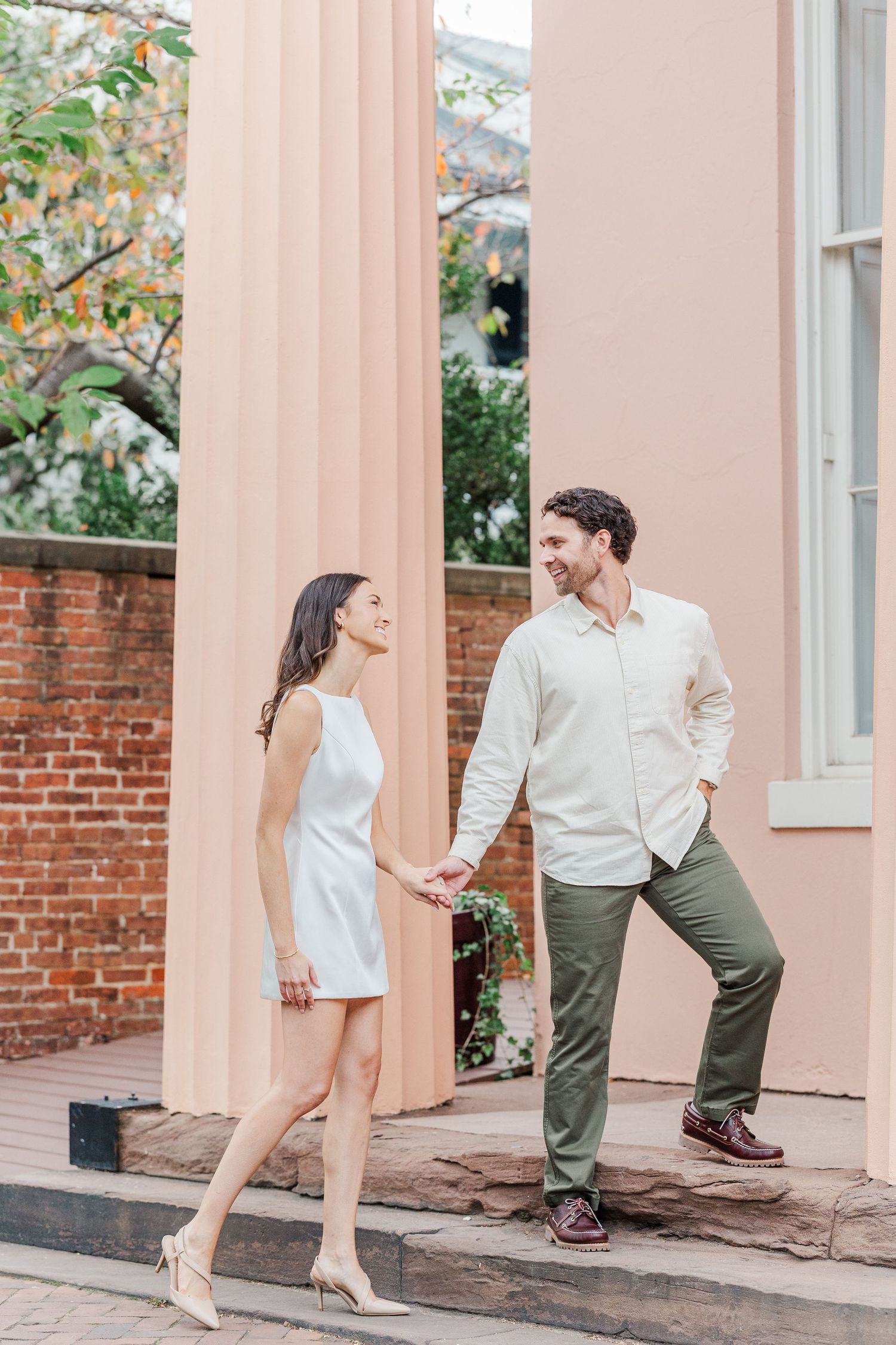 A playful series of photos showing a couple dancing and posing together on a pink-columned porch with brick walls.