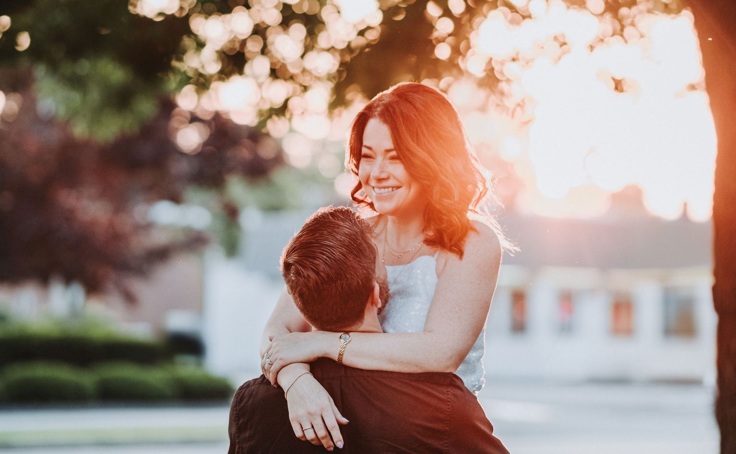 A couple shares a romantic moment during sunset in a garden setting with soft golden lighting.