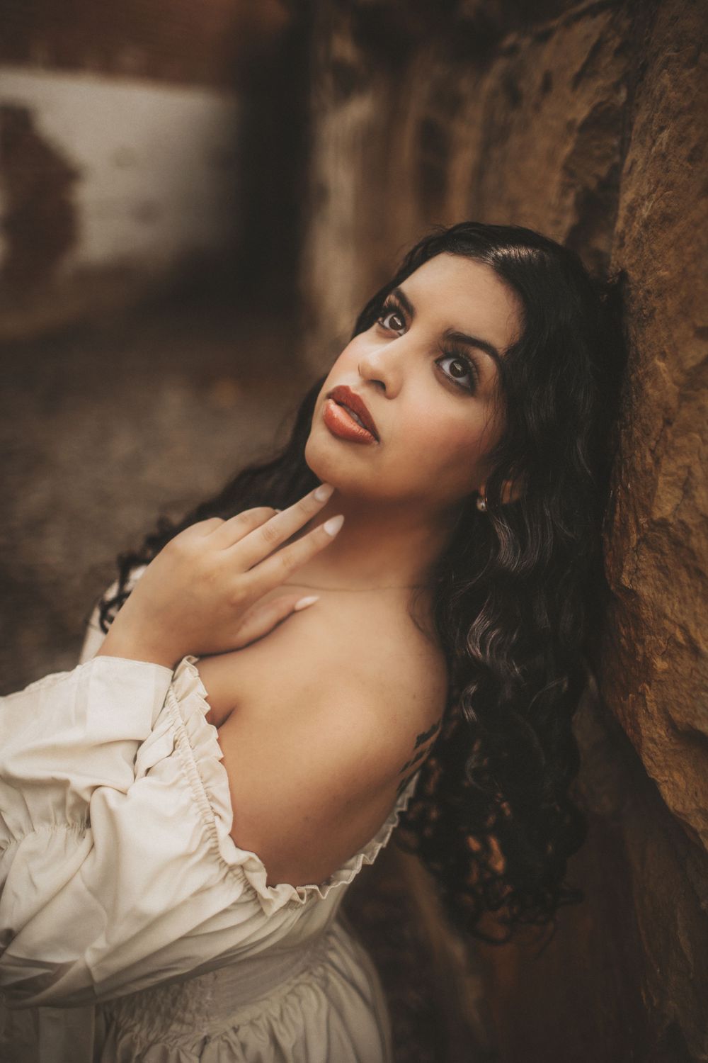 Cinematic portrait of a woman with long dark hair in a flowing dress, captured in warm natural light with a moody, romantic style