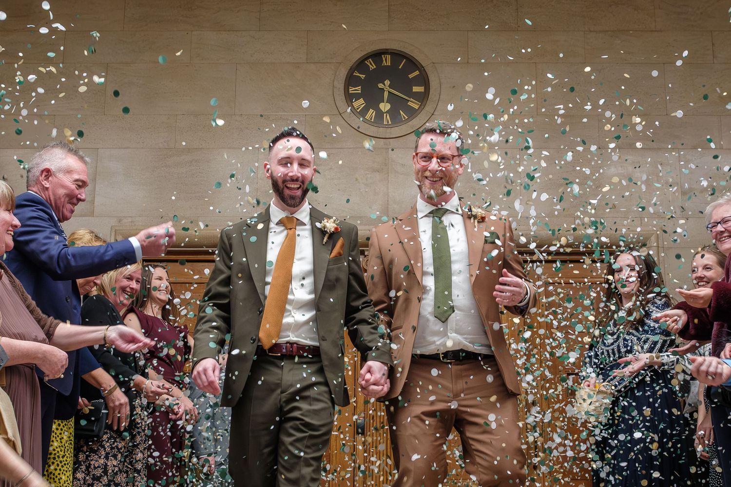A couple of grooms enjoy a confetti moment outside a wedding venue