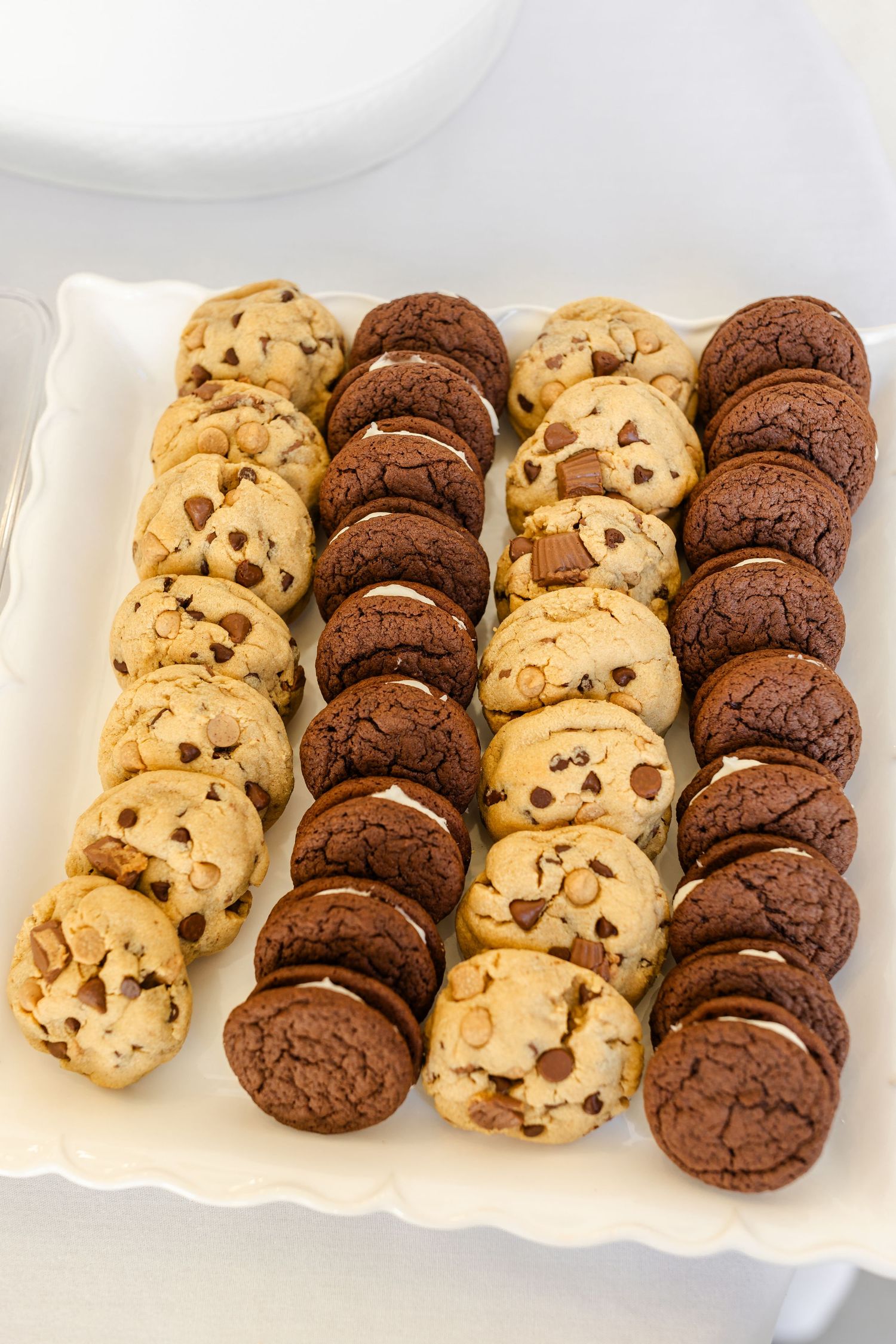 Rows of freshly baked chocolate chip and double chocolate cookies arranged neatly on a white serving platter by Chelsee Rawe Photographer