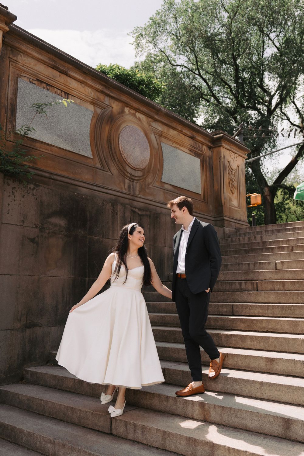 A couple shares a moment on stone steps against a rustic wall backdrop.