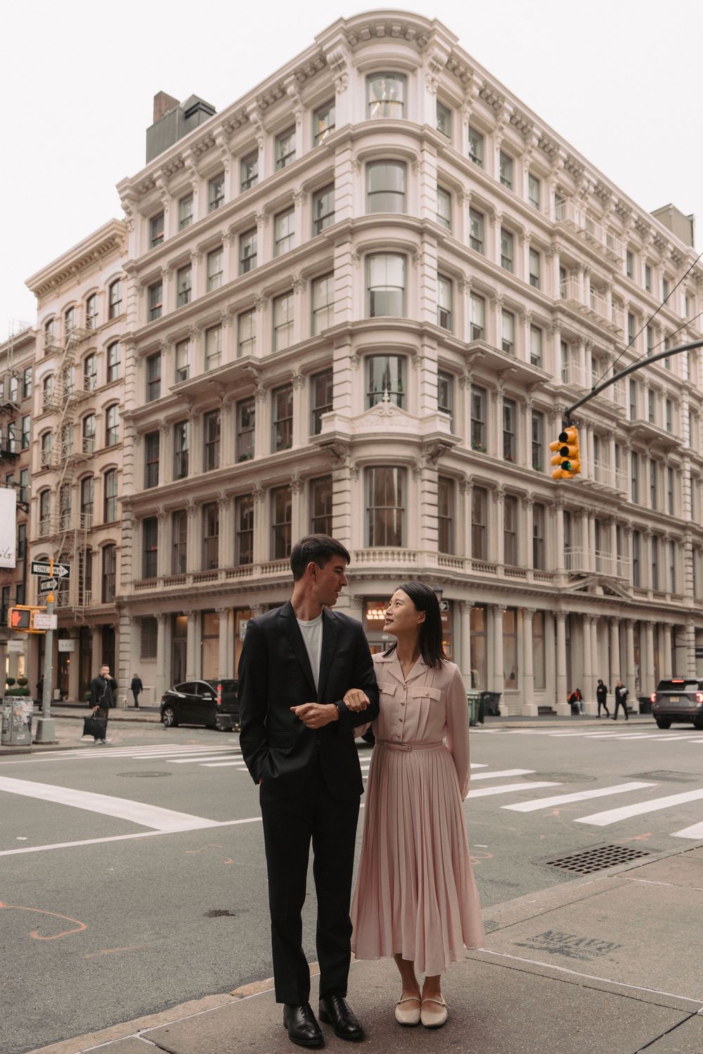 Couple standing in front of historic cast-iron architecture in SoHo, New York City.
