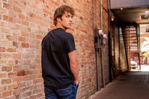 Teen walking through brick hallway wearing dark clothing.