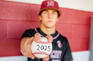 Baseball player holding up ball showing class of 2025.