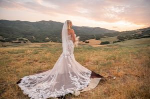 Dramatic mountain vista with flowing lace wedding dress in foreground during sunset.