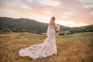 Beautiful wedding dress train spread across mountain meadow at dusk.