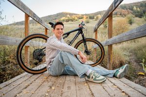 Senior portraits with mountain bike on wooden bridge in natural setting.