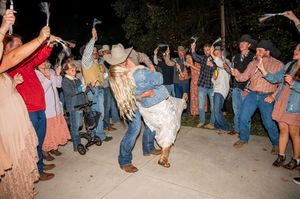 Wedding guests dancing and celebrating at an outdoor nighttime reception.