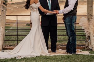 Rustic outdoor wedding ceremony setup with wooden arch and floral decorations on a ranch.