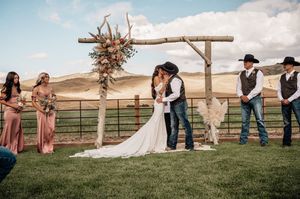 Wedding ceremony site with wooden cross arch and floral arrangements in a scenic mountain setting.