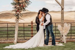 Intimate outdoor wedding ceremony under a rustic wooden arch with mountain views.