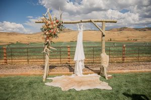 Outdoor wedding ceremony site with wooden arch and white fabric against desert landscape.