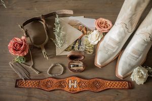 Wedding details including white shoes, rings, and delicate accessories on wooden surface.