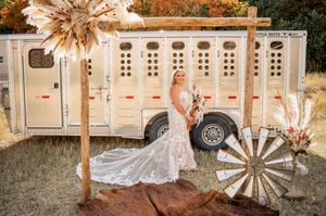 Rustic wedding reception setup with vintage decor, hay bales, and white portable restroom trailers in an outdoor setting.