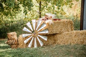 Rustic outdoor wedding venue with decorative wooden windmill elements and natural landscaping.