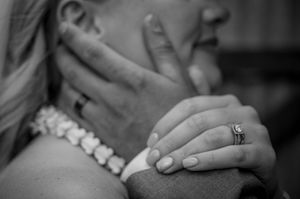 Close-up detail of hands with wedding rings in black and white photography.