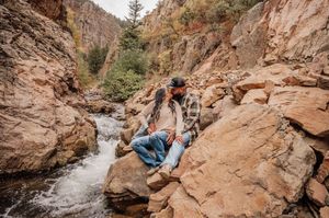Scenic canyon with red rock formations and flowing stream in mountain setting.