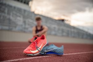 Running shoes on a track with stadium bleachers in the background at sunset.