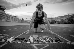 Track athlete in starting position with running shoes lined up on the track.