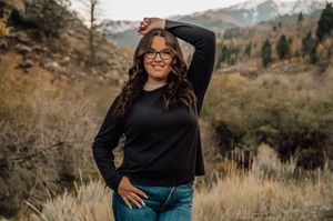 Black sweater and jeans outfit against autumn mountain landscape background.