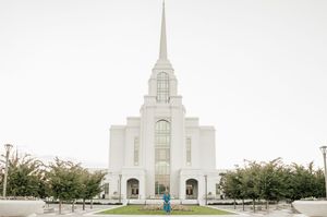 White Mormon temple with tall spires photographed against a bright sky.