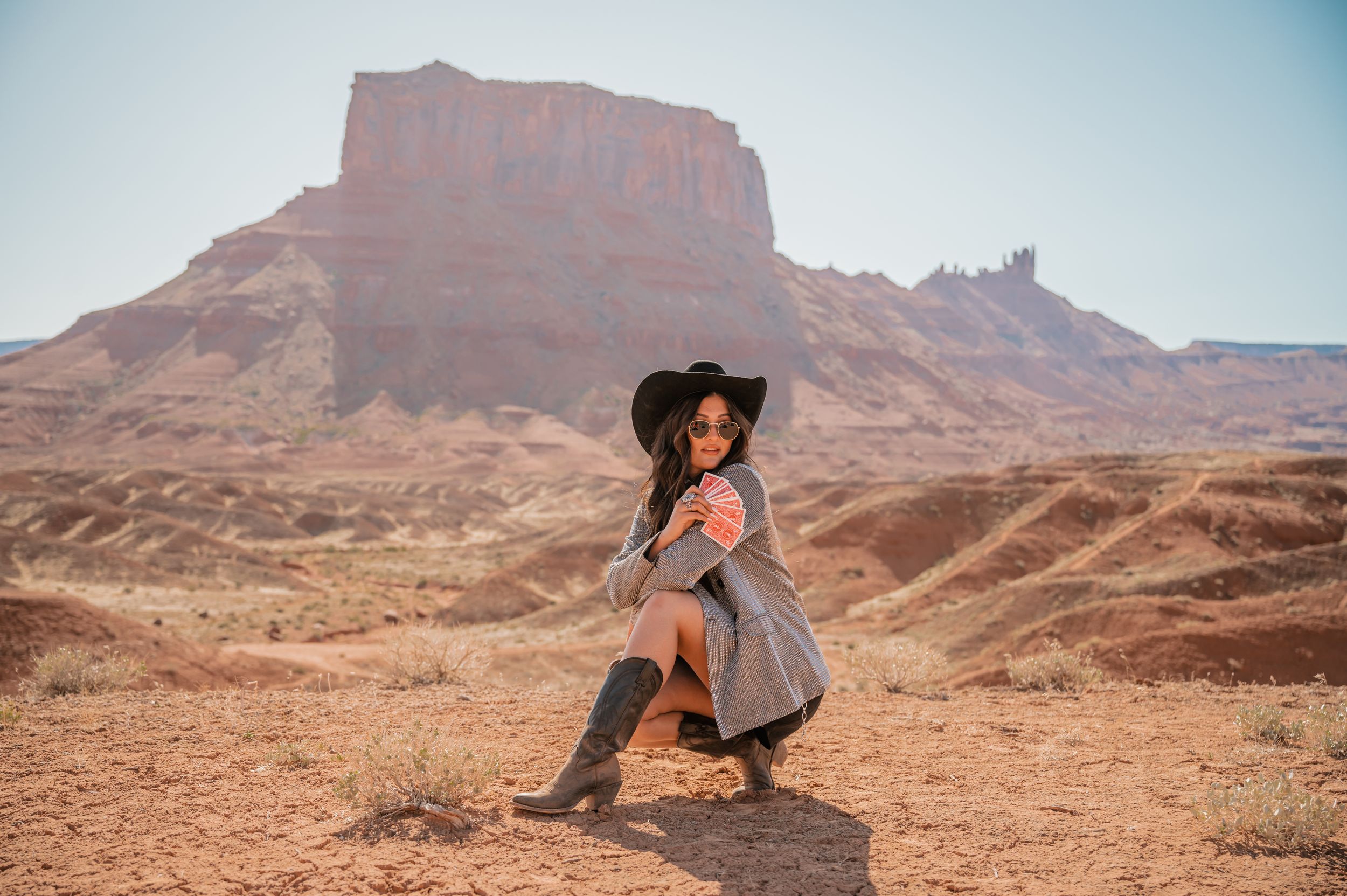 A western-styled photo shoot featuring dramatic poses in front of desert rock formations.