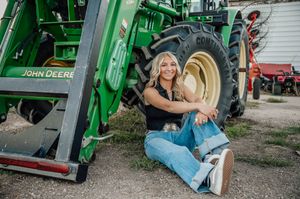 Casual portrait next to a large green John Deere tractor wheel.