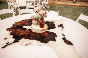 Wedding reception tables decorated with cowhide accents and rustic centerpieces.