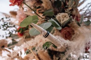 Floral arrangements with red roses and eucalyptus leaves in rustic wedding decor.