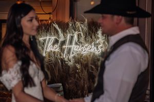 Wedding celebration in rustic barn venue with dried wheat stalks and ambient lighting.
