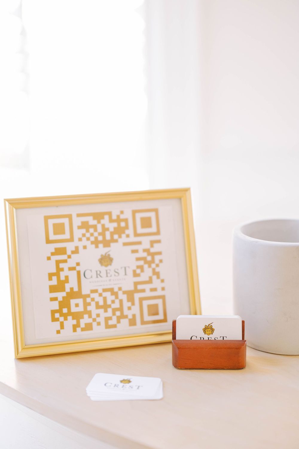 Elegant framed QR code display with business cards and white coffee mug on minimalist white surface.