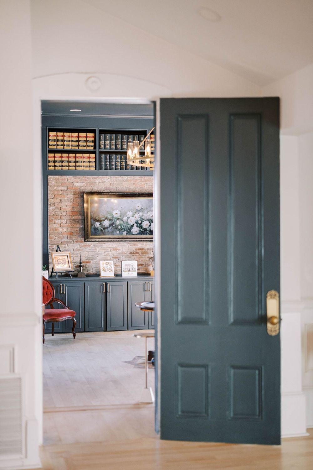 Large teal double doors open to reveal a modern interior space with brick accent walls.
