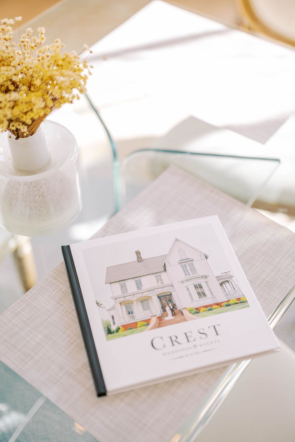 Custom house illustration on white paper with yellow flowers in a vase displayed on a textured surface.
