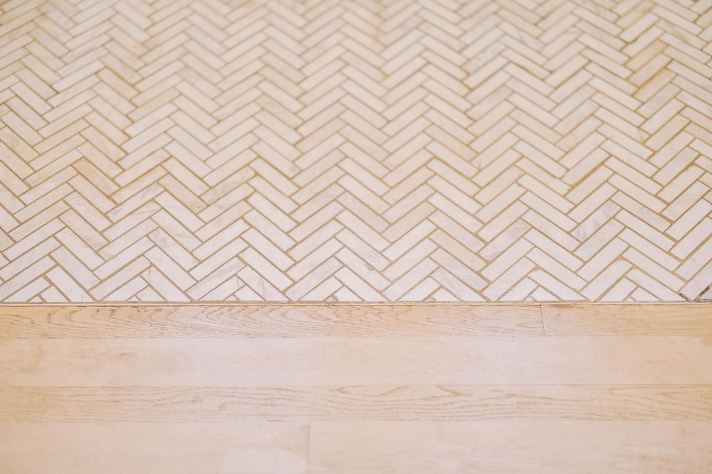 Herringbone pattern wood flooring in light natural tones.